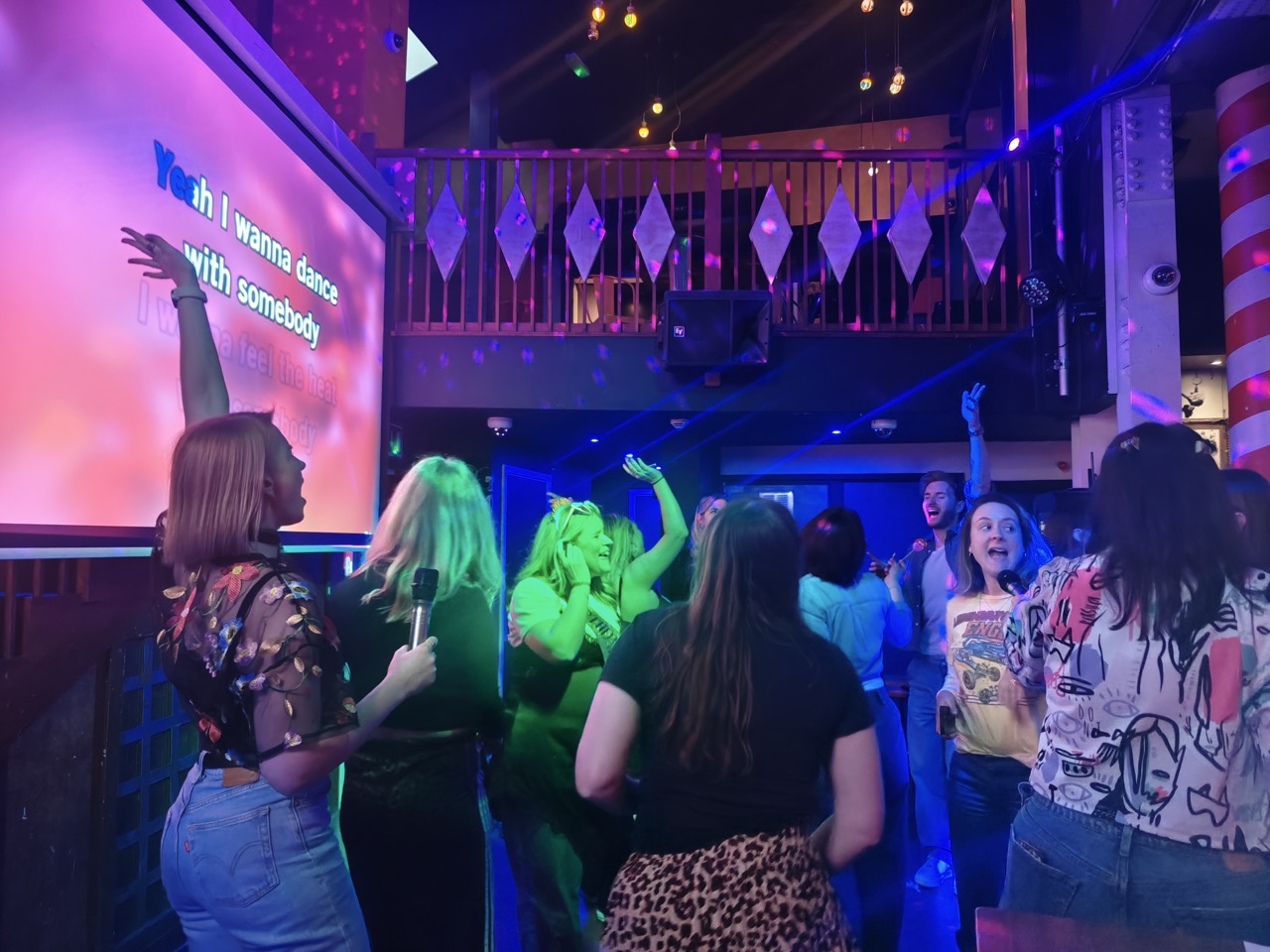 Guests dancing and singing at a karaoke DJ hire night in a London bar