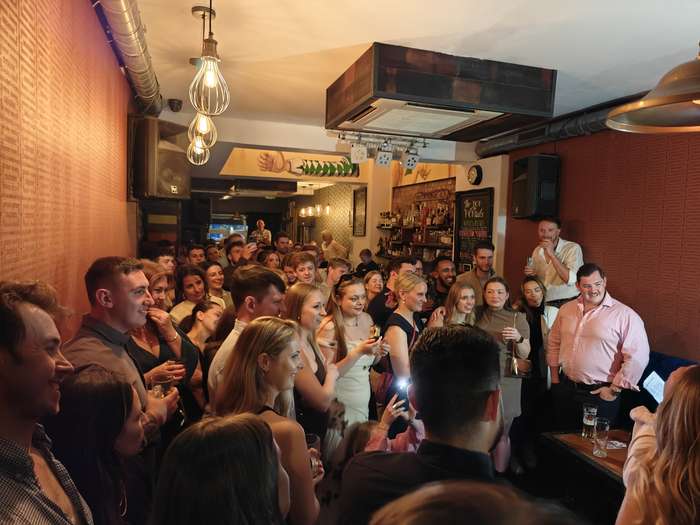 Guests toasting drinks at the bar during a London party hosted by Party Night London