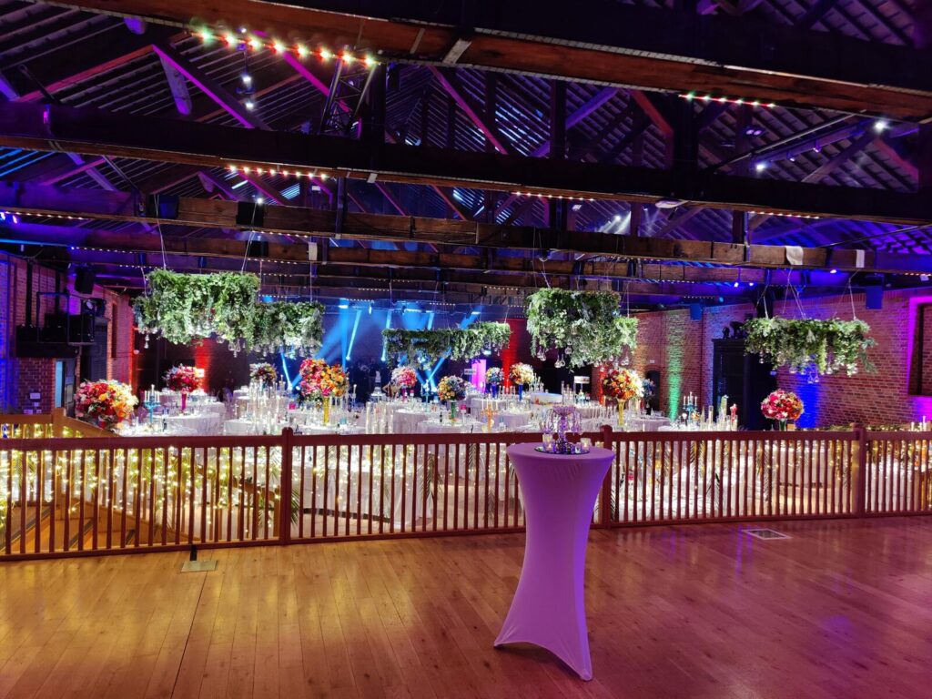 Wedding reception at The Brewery, Moorgate — candlelit tables with colourful floral arrangements and hanging greenery