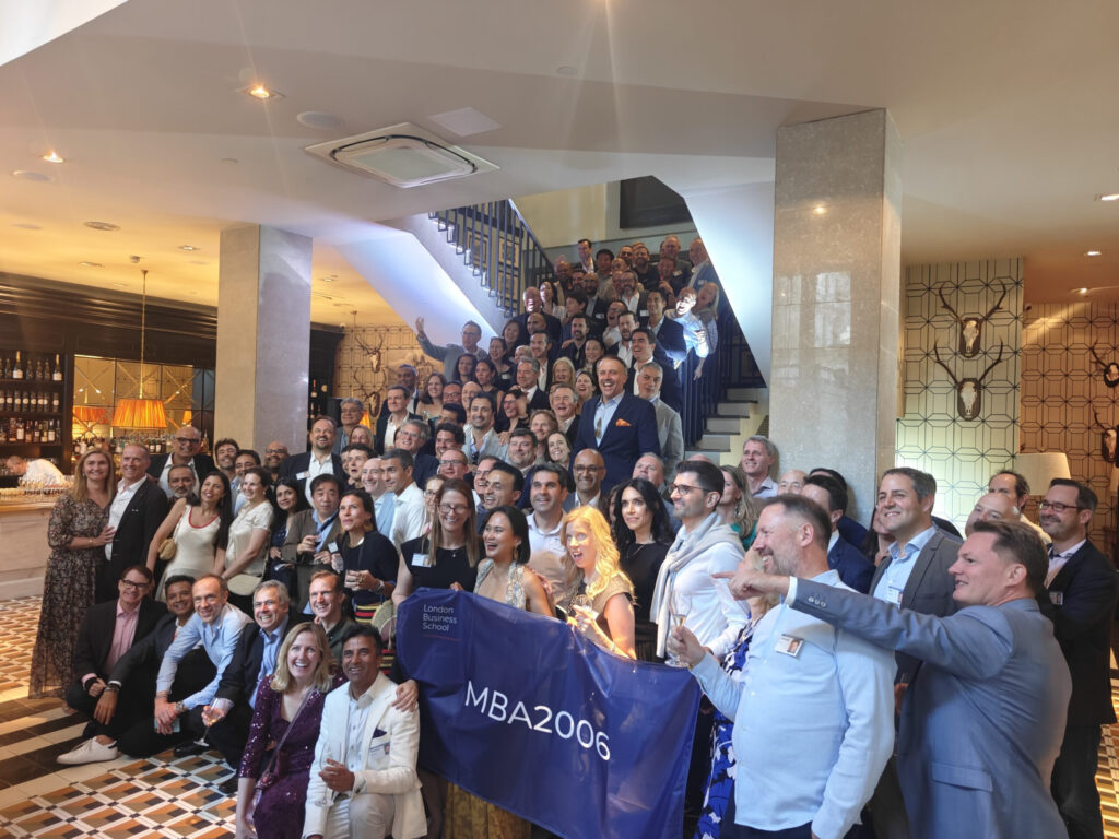 Large group of London Business School MBA2006 alumni posing on the staircase at Hispania holding an MBA2006 banner